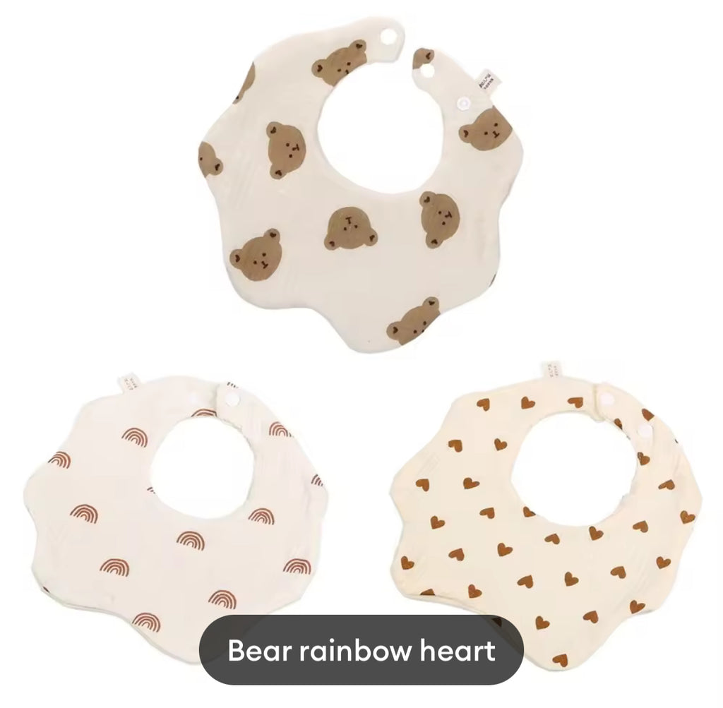 Three baby bibs with bear, rainbow, and heart patterns on a white background.
