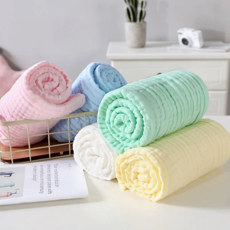 Stack of rolled-up towels in pink, blue, green, and yellow on a white surface.