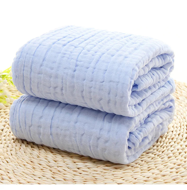 Two folded light blue blankets on a woven mat