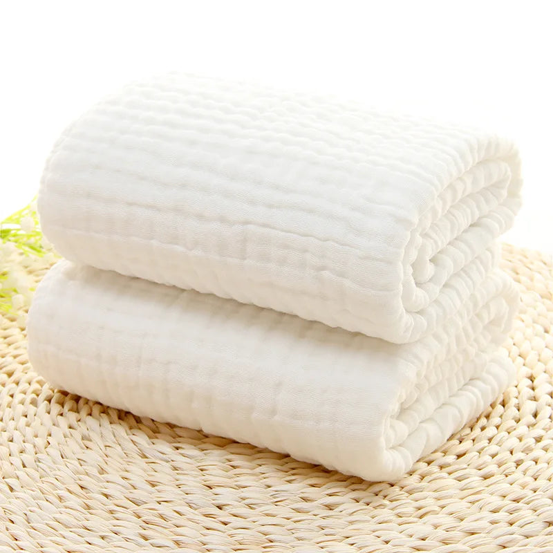 Two white towels stacked on a woven mat