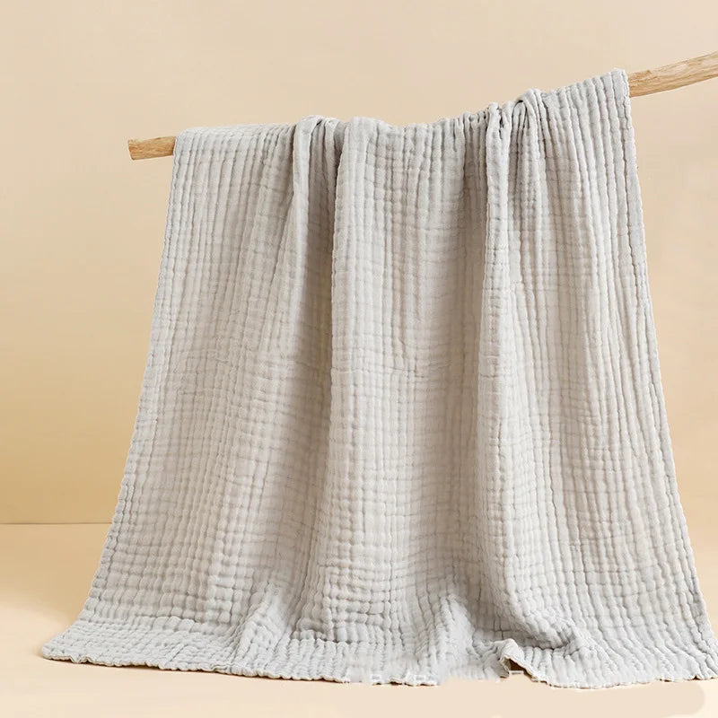 Textured gray blanket draped over a wooden rod against a beige background
