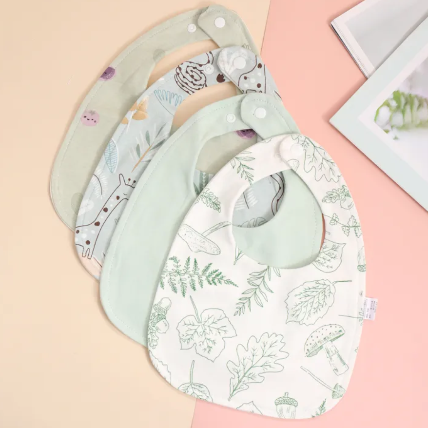 Set of three baby bibs with different patterns on a pink background