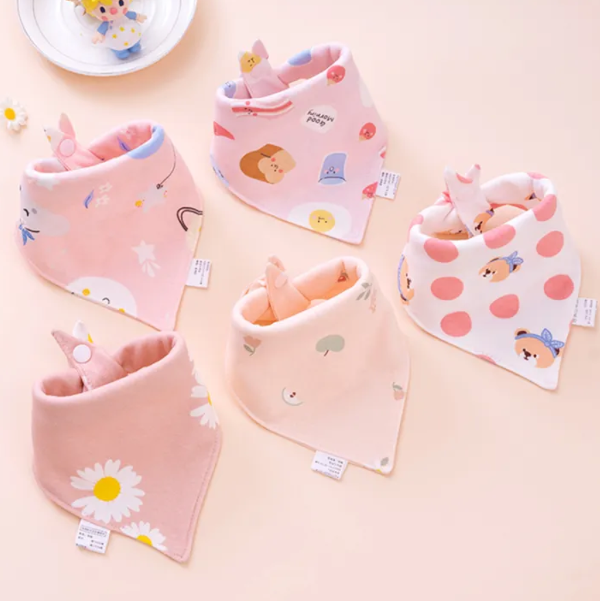 Set of colorful baby bibs with various patterns on a light pink background