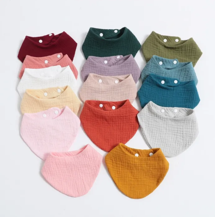 Collection of colorful baby bibs arranged in a grid on a light background