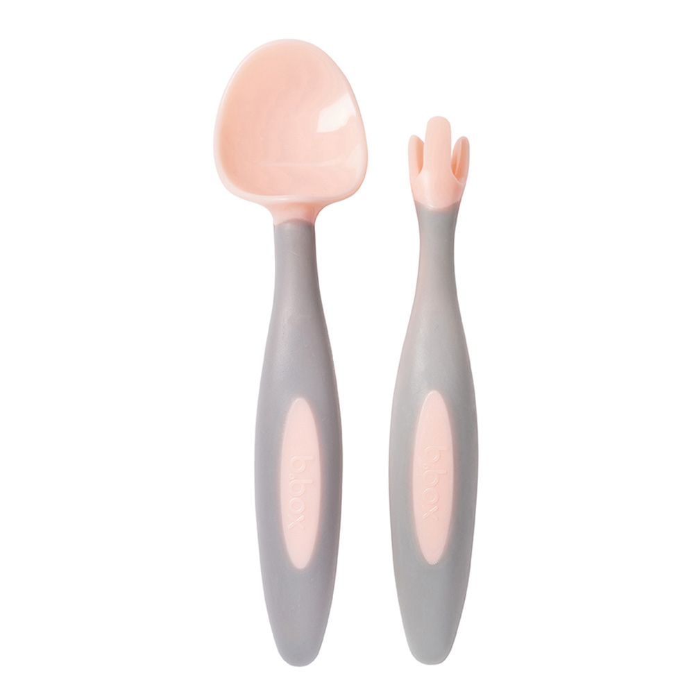Set of baby spoon and fork with pink ends and gray handles on a white background